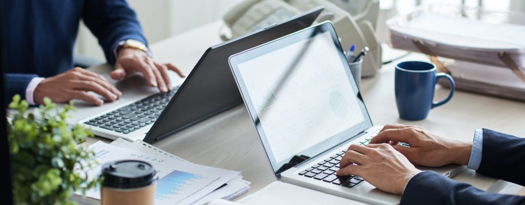 Cropped image of business people working on laptops in office